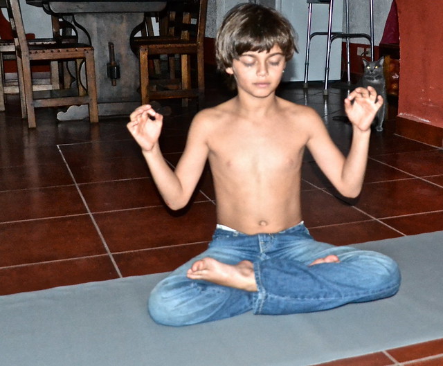 kid doing yoga while sitting on a gaiam travel yoga mat