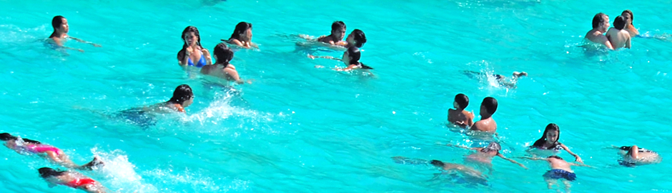 Fotografía de unas gentes bañándose en una piscina pública, completamente ajenos al peligro que se cierne sobre ellos