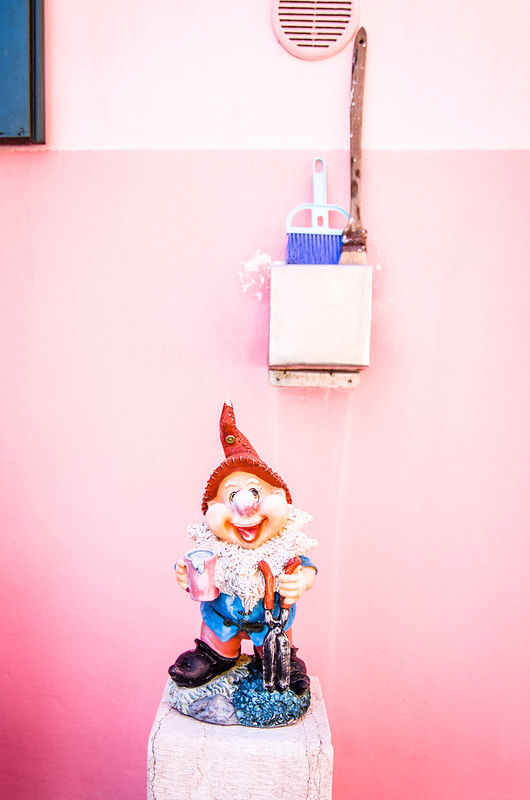 A gnome takes a break outside a peachy pink house in Burano, Italy.
