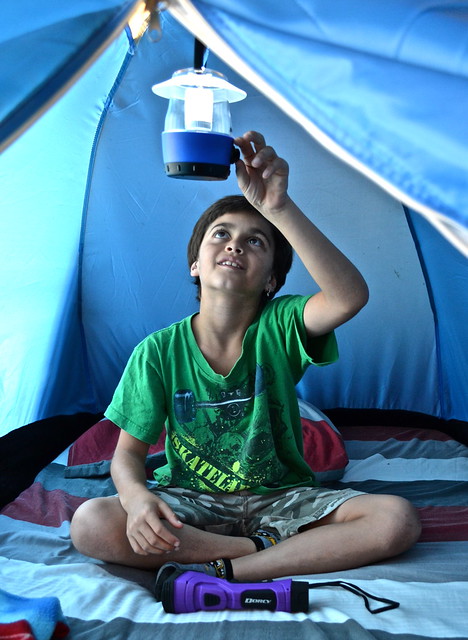 kid playing with dorcy camping lantern inside a tent