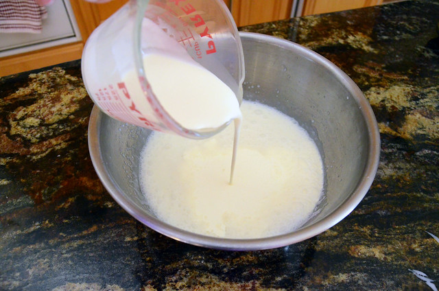 Heavy whipping cream being poured on top of the whole milk and cream of coconut mixture.