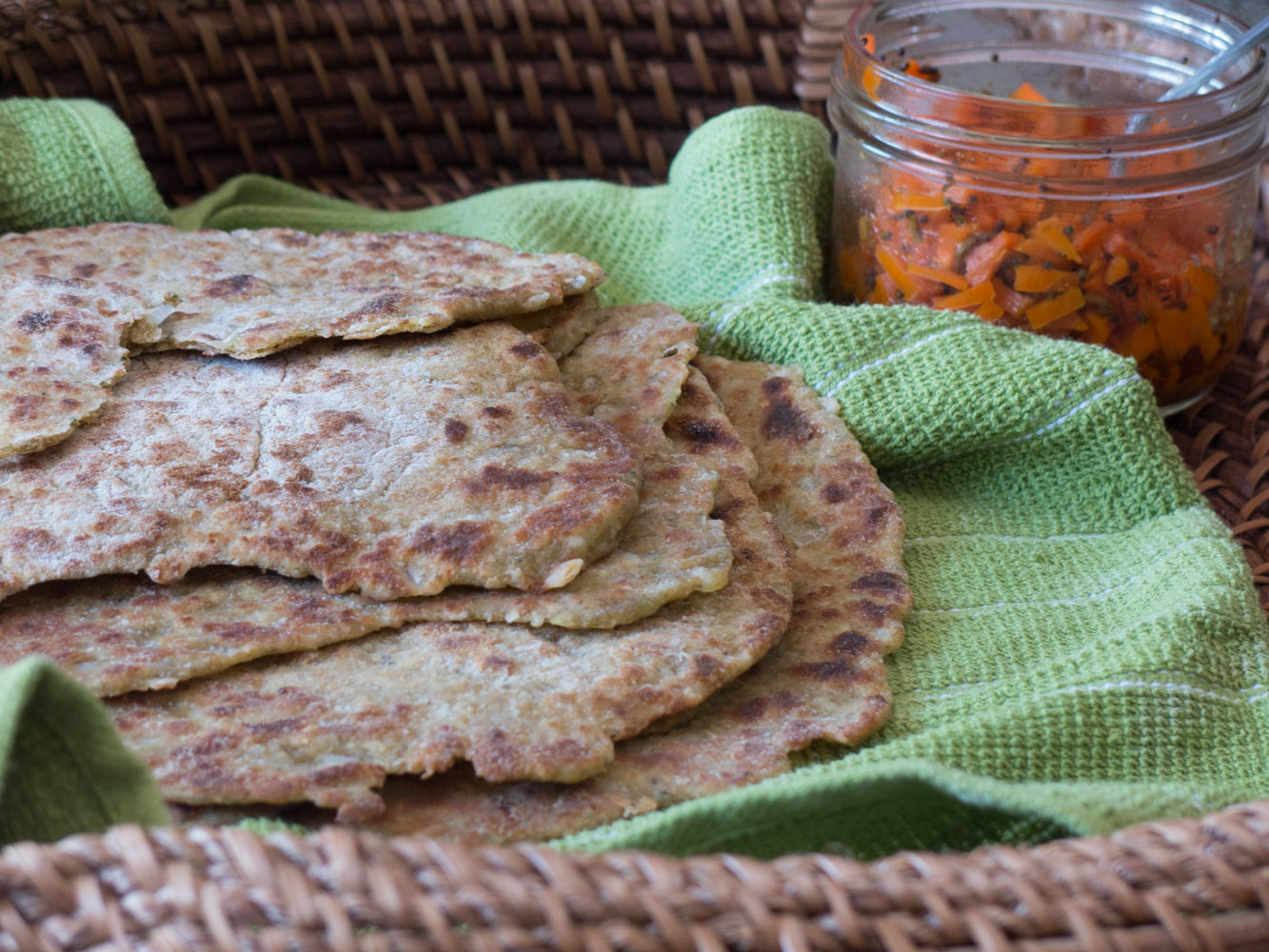 zucchinie and thyme flatbreads in a basket with a green napkin, served with carrot relish