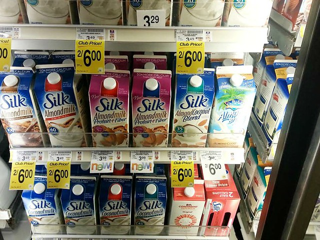 Dairy case at grocery store with Silk almond milk in cartons on shelf.